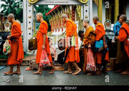 Luang Prabang / Laos - JUL 06 2011: monks during their early morning round around the town to collect their alms Stock Photo