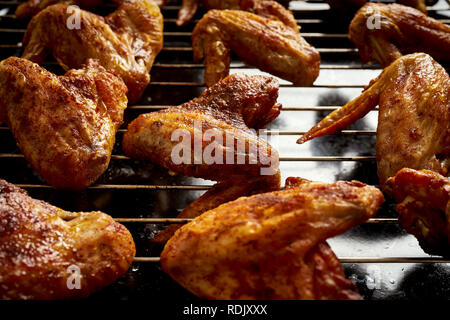 Delicious hot grilled chicken wings on black grid grill. Stock Photo