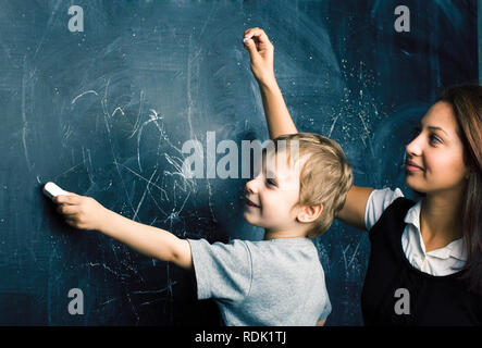 little cute boy in glasses with young real teacher, classroom studying at blackboard school kido Stock Photo