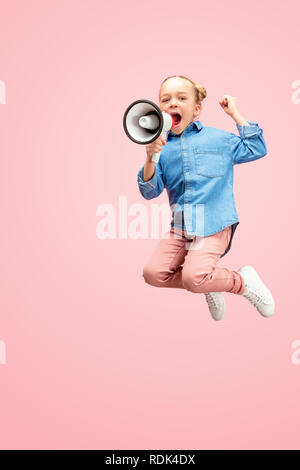 Beautiful young child teen girl jumping with megaphone isolated over pink background. Runnin girl in motion or movement. Human emotions,, facial expressions and advertising concept Stock Photo
