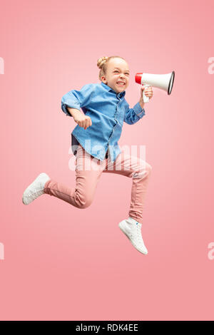 Beautiful young child teen girl jumping with megaphone isolated over pink background. Runnin girl in motion or movement. Human emotions,, facial expressions and advertising concept Stock Photo