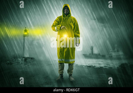 Man at the coast coming in raincoat with glowing lantern concept  Stock Photo