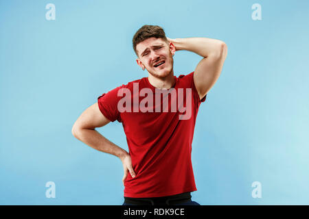 Man having headache. Isolated on blue background. Business man standing with pain isolated on trendy pink studio background. Male half-length portrait. Human emotions, facial expression concept. Stock Photo