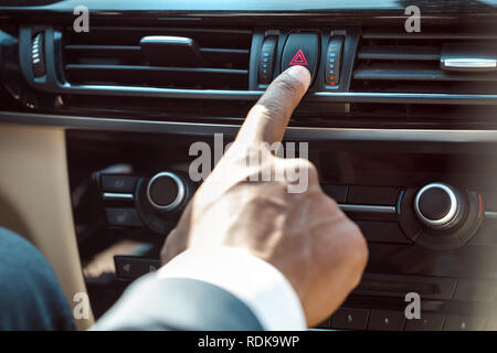 Young businessman driver sitting inside car pushing emergency button close-up Stock Photo