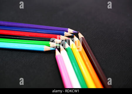 Different wooden colored pencils. Isolated on the black background. Stock Photo