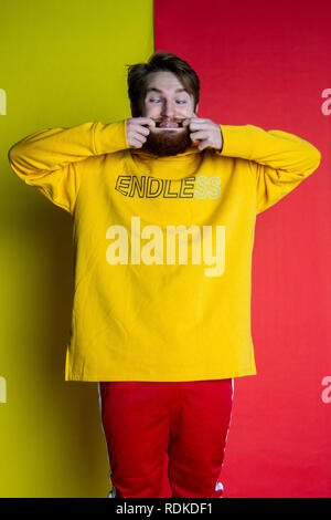 Fashion shot of male posing into the camera wearing clothes that match his backdrop Stock Photo