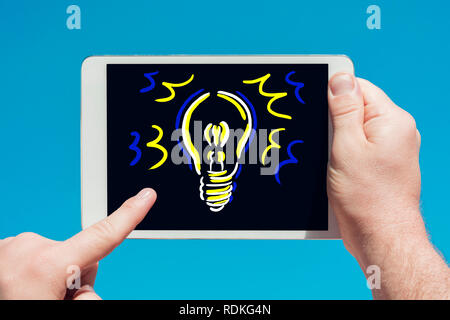 Man holding a tablet device and touching the screen with a finger with blue sky in background. Stock Photo