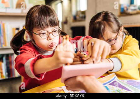 Dark-eyed sunny child playing with her groupmate in kindergarten Stock Photo