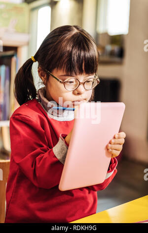 Beautiful little sunny girl feeling joyful while drawing pictures Stock Photo
