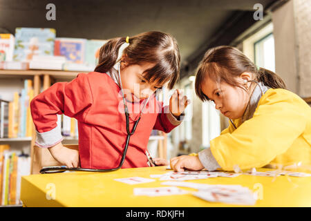 Cute sunny children wearing bright sweaters playing together Stock Photo