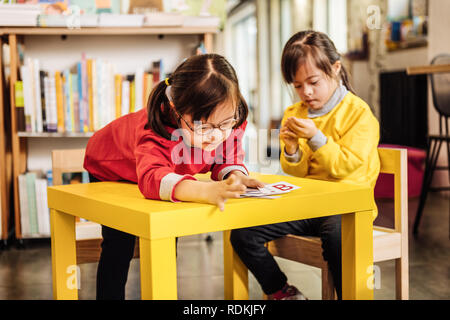 Cute dark-haired pleasant sunny child learning letters in kindergarten Stock Photo