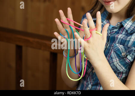 Child playing classic, old-school string game and didactic toy with her fingers, making cats cradle, developing her motor skills. IQ, education, intel Stock Photo