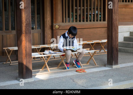 Kumamoto, Japan - November 11, 2018: Little boy is reading a book in front of Izumi shrine in Suizenji Garden, Suizenji Jōjuen
