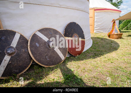 Medieval wooden and metal shields for close combat used in wars next to the white tent Stock Photo