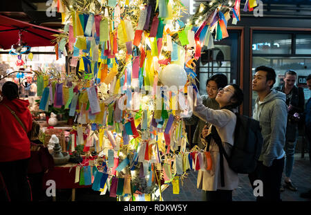 Patrons at an outdoor mall read wishes written on Tanzaku, small pieces of paper that are hung on a wishing tree, located in the Little Tokyo. Stock Photo