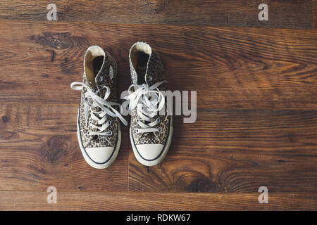 Converse all star shoes / trainers with an animal print, photographed  against wooden floor Stock Photo - Alamy