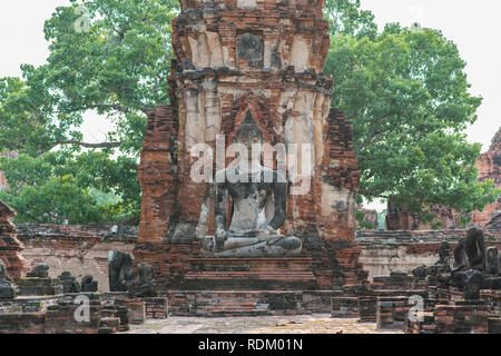 Sitting Buddha at Wat Phra Mahathat (Mahatat) in Ayutthaya, Thailand. Ruins of a decorated brick tower and a statue of an ancient Buddhist temple Stock Photo