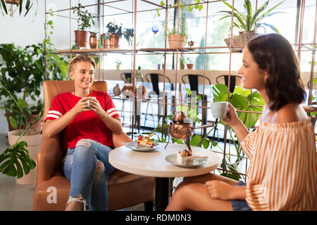 female friends drinking tea and talking at cafe Stock Photo