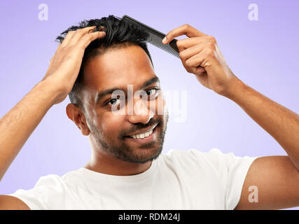 happy indian man brushing hair with comb Stock Photo