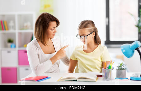 strict mother talking to daughter doing homework Stock Photo