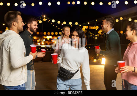 friends with drinks dancing at rooftop party Stock Photo