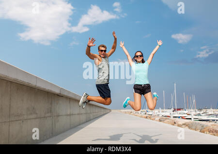 happy couple in sports clothes jumping on pier Stock Photo