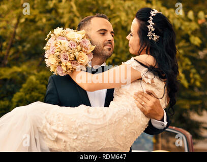 Just Married Husband Carries Her Wife in His Arms Stock Photo