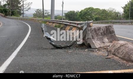 A close up view of the metal and concrete bolck barrier on the side of a freeway or motorway that has been damaged by a car or motor vehicle crashing  Stock Photo