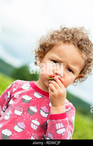 Small girl eating strawberry Stock Photo