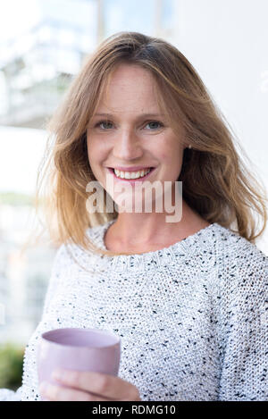 Smiling pregnant woman holding mug and touching her belly Stock Photo ...