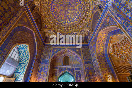 The interior of a Madrasa decorated with blue white and gold ceramic tiles in traditional Islamic patterns in Samarkand. Stock Photo