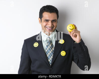 PORTRAIT OF CORPORATE EXECUTIVE wearing smile badges and holding a smiley ball Stock Photo