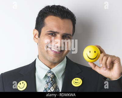 PORTRAIT OF CORPORATE EXECUTIVE wearing smile badges and holding a smiley ball Stock Photo