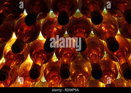 Close up rows of backlit white wine glass bottles stacked aging in winery cellar Stock Photo