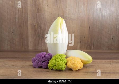 fresh endive (Cichorium endivia) and decoratif cauliflower on natural wooden background with highlight and shadows Stock Photo