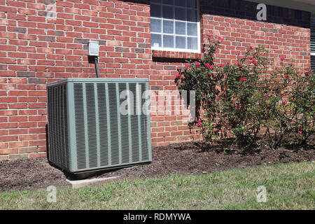 Air conditioner unit. clean modern, at a home with rose bushes Stock Photo