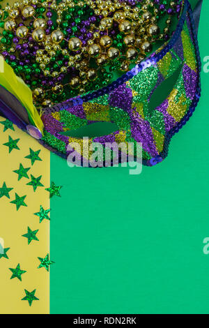 mardi gras mask with beads and stars on mottled green and yellow background Stock Photo