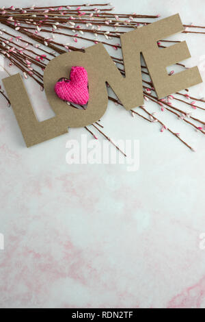 Love with pink knitted heart and spring flower buds on pink marble background Stock Photo
