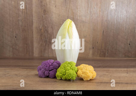 Endive (Cichorium endivia) and decoratif cauliflower on natural wooden background with highlight and shadows Stock Photo