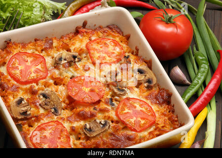 Casserole with tomato and mushrooms on a wooden background Stock Photo