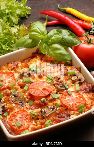 Casserole with tomato and mushrooms on a wooden background Stock Photo