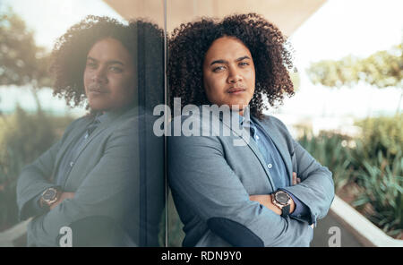 Young mixed race guy with curly afro looking into camera with arms crossed Stock Photo