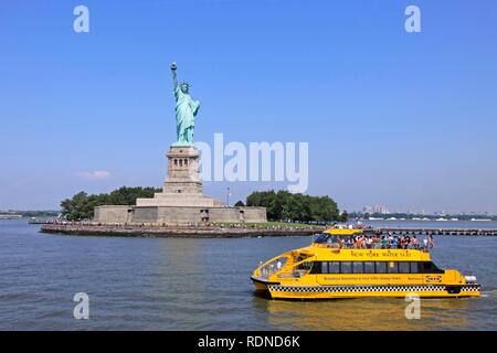 Water taxi crossing in front of the Statue of Liberty, New York, USA, North America Stock Photo