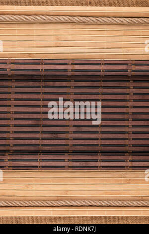Bamboo mat curled in the form of a manuscript and rope on sackcloth, with space for your text. Top view Stock Photo