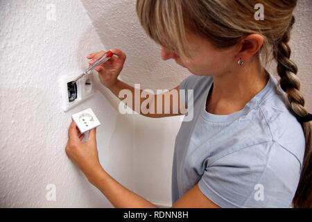 Young woman installing a power socket Stock Photo