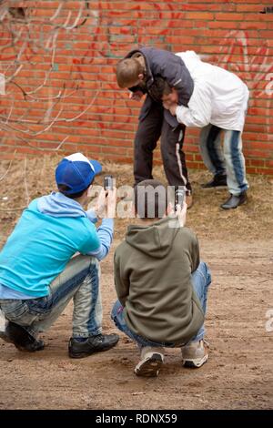 Two boys fighting each other and being filmed by two other boys with their cell phones, posed scene Stock Photo