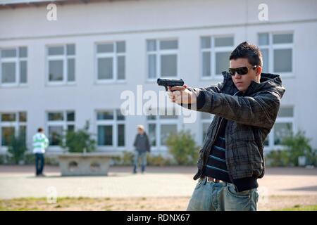 Teenager with a Softair pistol on a school playground, posed scene Stock Photo