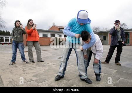 Two fighting boys are being filmed by three other teenagers with their mobile phone, reenactment Stock Photo