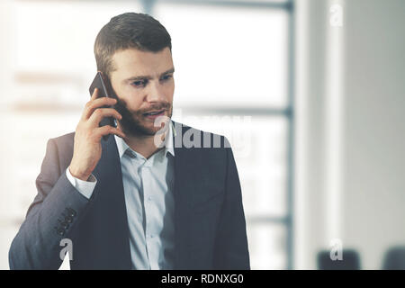 business communication - young businessman talking on the phone in office Stock Photo