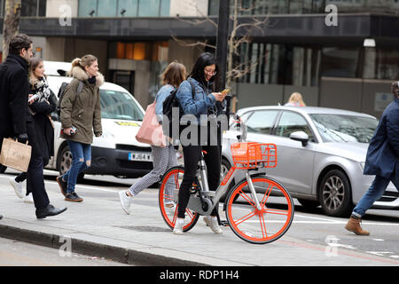 woman on hire bike looking at phone Stock Photo